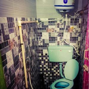 a bathroom with a green toilet and a tiled wall at Sai Homestay in Kanchipuram +19 photos