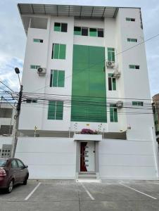 a white building with green windows and a parking lot at Hermoso apartamento #13 piso 3 in Machala