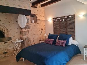 ein Schlafzimmer mit einem blauen Bett und einer Ziegelwand in der Unterkunft L 'Aupinouse Chambre double Pivoine avec salle d'eau privative in La Suze-sur-Sarthe