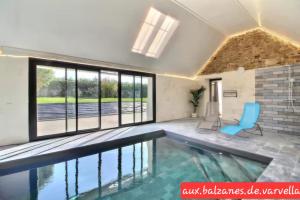 een zwembad met een blauwe stoel in een kamer met ramen bij Piscine intérieure privée chauffée spa toute lannee disponible minimum 2 nuits in Ploudaniel