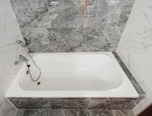 a white bath tub in a bathroom with marble tiles at Seaside 3 in Marsaskala