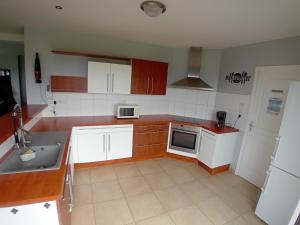 Una cocina con gabinetes blancos y un fregadero. en Gîte du Buron 6 8 personnes, en Longueville