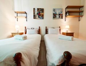 two beds in a room with white sheets at Seaside 4 in Marsaskala