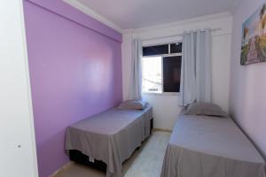 two beds in a room with purple walls and a window at Apto com ar-condicionado a 350m do mar em Aracaju in Santa Maria
