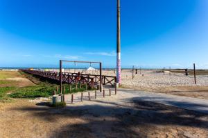 a pier on the beach with a building in the background at Apto com ar-condicionado a 350m do mar em Aracaju in Santa Maria