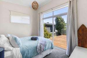 a bedroom with a bed and a sliding glass door at Sea you on Leo in Waihi Beach