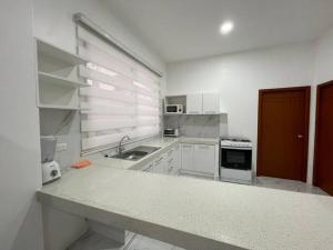 マチャラにあるConfortable Apartamento # 2 planta bajaのシンクとコンロのある白いキッチン +6枚の写真