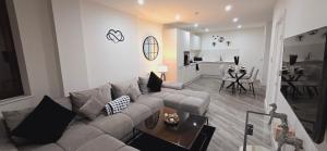 a living room with a gray couch and a kitchen at Abbey Corner By Nivaas-Located in the heart of the city centre-5 minute walk to train station-20 minutes to London via train in Reading +33 photos