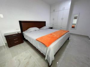 a bedroom with a large bed with an orange blanket at Apto #18 con Hermosa Vista piso 3 in Machala