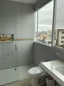 a white bathroom with a toilet and a window at Apartamento Moderno con vista a calle, Piso 3, #12 in Machala