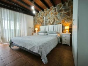 Un dormitorio con una cama y una pared de piedra. en Casa Zamora, en Los Realejos