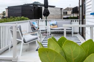 Un balcón con dos sillas y una sombrilla. en The Urban Escape Stylish 1-Bed in Prime Downtown, en Mount Maunganui