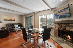 een woonkamer met een tafel, stoelen en een open haard bij Lakeview Condo - Lakefront Complex, Lake Views, Heated Pool in Big Bear Lake