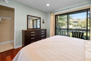 een slaapkamer met een bed, een spiegel en een raam bij Lakeview Condo - Lakefront Complex, Lake Views, Heated Pool in Big Bear Lake