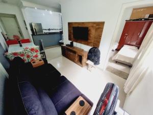 a living room with a couch and a tv at Edifício Plaza de Saint Martin in Santos