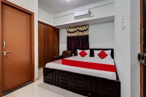a bedroom with a bed with red pillows and a door at Super Hotel O PM Hotels in Bengaluru