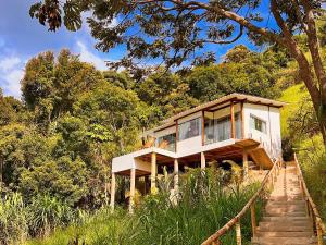 a house on the side of a hill with trees at Vivenda Apua Chalés in Piracaia