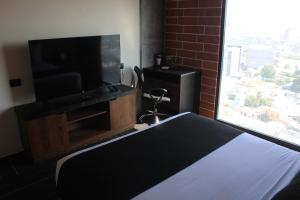 a bedroom with a bed and a flat screen tv at Hotel Ecovergel Santa Lucia in Monterrey