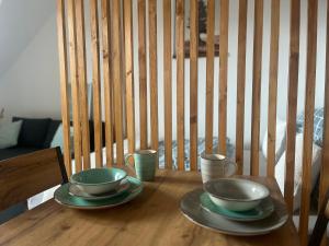a wooden table with two cups and plates on it at Apartmán Pavčina Lehota in Pavčina Lehota +2 photos