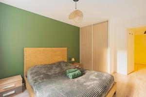 a bedroom with a bed with a green wall at Appartement tout équipé à 3 min Gare Annemasse - Idéal famille ou Pro - Parking inclus in Ville-la-Grand
