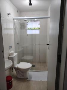 a white bathroom with a toilet and a shower at Villa Bali Maresias Lofts in Maresias