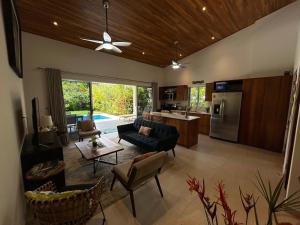 a living room with a ceiling fan and a kitchen at Villa Mariposa - Ojochal, Close To Everything in Ojochal