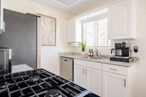 a kitchen with white cabinets and a stove top oven at Beacons Beach Cottage in Encinitas