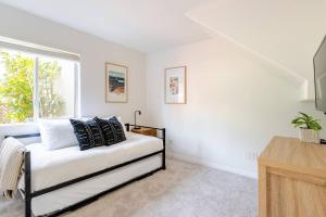 a white room with a bed and a window at Beacons Beach Cottage in Encinitas