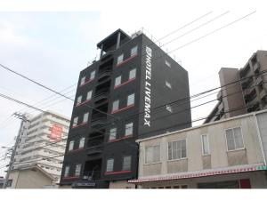 三原的住宿－HOTEL LiVEMAX Mihara Ekimae，一座黑色的建筑,旁边有一个标志