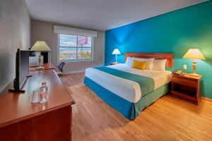 a hotel room with a large bed and a desk at Sierra Suites By HP Hotels in San Luis Potosí
