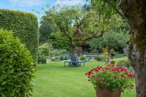 een park met een bankje en bloemen in het gras bij Cotswold Stable Cottage in Bibury