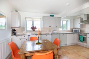 a kitchen with a wooden table and orange chairs at Cotswold Stable Cottage in Bibury