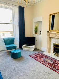 ein Wohnzimmer mit einem Kamin und einem blauen Stuhl in der Unterkunft Quiet apartment close to station & Stirling Castle in Stirling