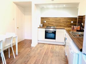 eine Küche mit weißen Schränken und einem Tisch und einem Herd in der Unterkunft Quiet apartment close to station & Stirling Castle in Stirling + 22 Fotos