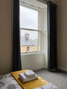 1 Schlafzimmer mit einem Fenster und 2 Handtüchern auf einem Bett in der Unterkunft Quiet apartment close to station & Stirling Castle in Stirling