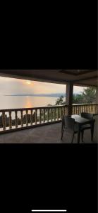 a table and a bench on a balcony with the ocean at KJT Travellers Inn in Guindulman