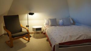 a bedroom with a bed and a chair and a lamp at Doktors Hus in Oldenswort