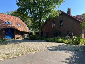 une maison en briques avec un arbre et une allée dans l'établissement Ferienhaus Gandur, à Osterby