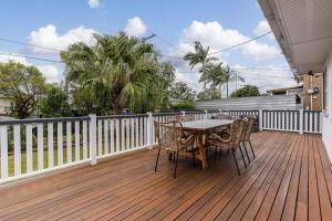 una terrazza in legno con tavolo e sedie. di Acacia Ridge Cottage - Firepit, Kids Cubby, Games a Brisbane