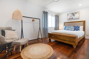 ein Schlafzimmer mit einem Bett, einem Stuhl und einem Tisch in der Unterkunft Acacia Ridge Cottage - Firepit, Kids Cubby, Games in Brisbane