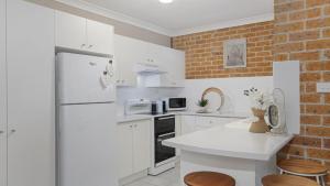 a kitchen with white appliances and a brick wall at Jervis Joy in Callala Beach