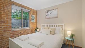 a bedroom with a white bed and a brick wall at Jervis Joy in Callala Beach +23 photos