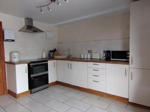 a kitchen with white cabinets and a black oven at Tyncellar Farm holiday cottages in Margam +13 photos