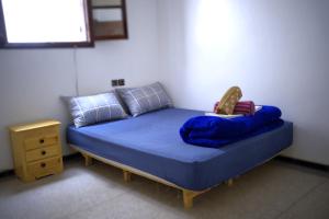 塔哈佐特Cozy By The Sea的一间卧室配有一张带蓝色床单的床和床头柜。 更多5张照片