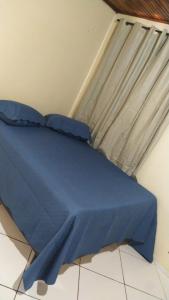 a bed with a blue comforter in front of a window at Casa da ilse in Foz do Iguaçu