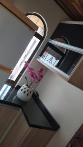 a vase with flowers sitting on a table in front of a window at Casa da ilse in Foz do Iguaçu