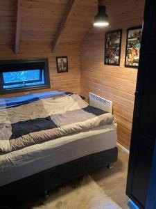 une chambre avec un lit dans une pièce en bois dans l'établissement Very cozy cottage, Rauðará, with sauna, à Gilsbakki