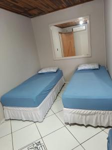 two beds in a room with a mirror at Casa da ilse in Foz do Iguaçu