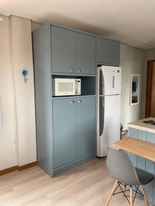 a kitchen with blue cabinets and a white refrigerator at Floripa Jurerê, pé na areia! Apto 6 in Florianópolis