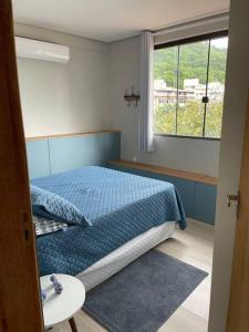 a bedroom with a blue bed and a window at Floripa Jurerê, pé na areia! Apto 6 in Florianópolis